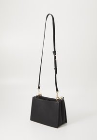 Black faux leather handbag with a structured shape, adjustable long strap, gold-tone hardware, and a textured surface.