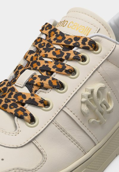 Αθλητικό παπούτσι εκρού με κορδόνια λεοπάρ, χρυσό κείμενο "Roberto Cavalli" στη γλώσσα και ανάγλυφο διακοσμητικό λογότυπο στο πλάι.