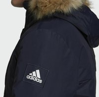 Granatowa kurtka puchowa z kapturem wyłożonym futrem, z białą naszywką logo Adidas na górnej części rękawa oraz teksturowanym materiałem dla lepszej izolacji.
