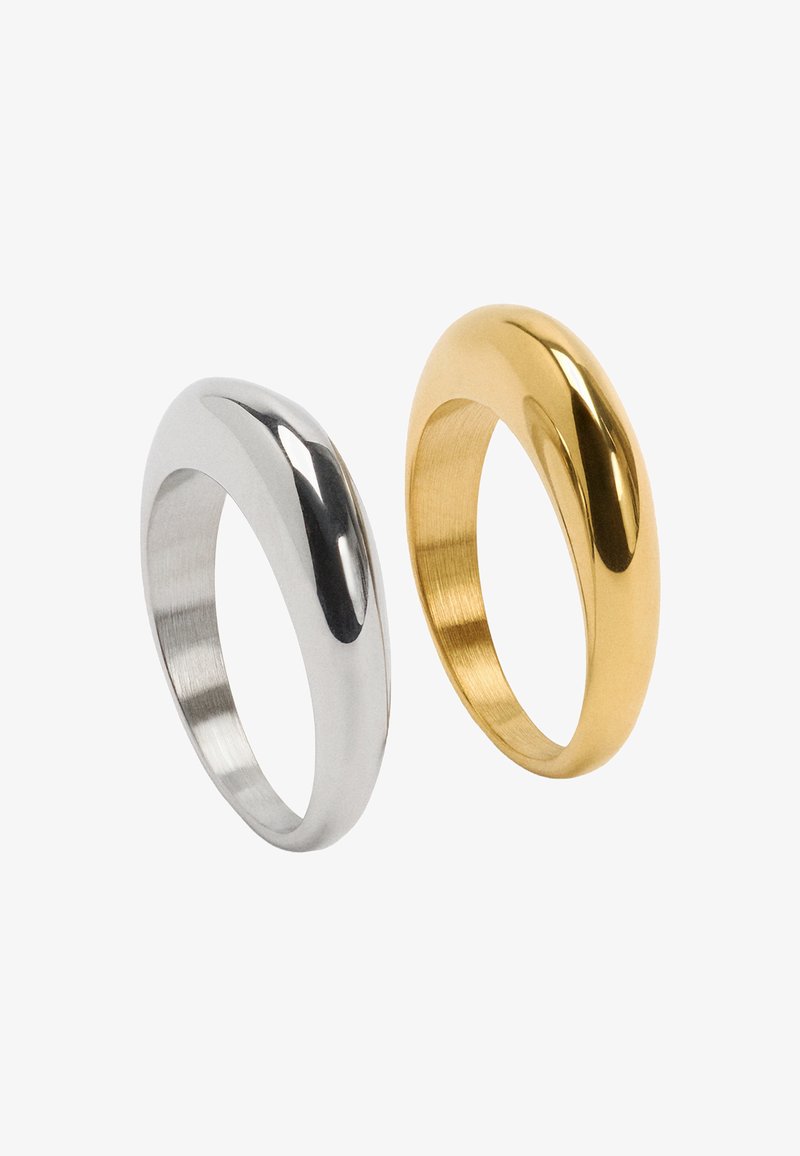 Dwa pierścienie: jeden z polerowanego srebrnego metalu o gładkiej fakturze, drugi z satynowanego złota z błyszczącym wykończeniem. Oba mają zaokrąglony kształt.