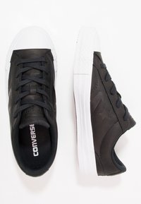 Sneakers in pelle nera con suole in gomma bianca, dotate di punta rotonda, chiusura con lacci e logo a stella impresso sui lati.