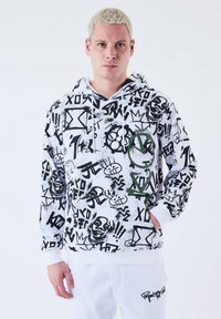 Sudadera blanca con un diseño gráfico en aerosol negro y verde, que presenta formas abstractas, personajes y patrones; puños y dobladillo blancos.