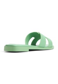 Sandale à semelle plate vert menthe, avec deux lanières découpées et une texture lisse et mate. Design minimaliste avec un profil épuré.