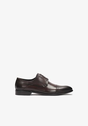 Scarpa da cerimonia in pelle marrone con una superficie liscia, punta arrotondata e design con lacci. Presenta un delicato dettaglio di cucitura lungo la tomaia.
