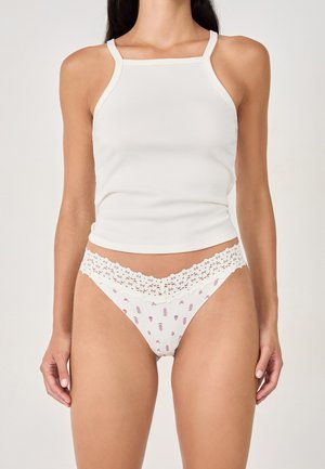 Débardeur blanc à côtes avec bretelles fines associé à une culotte blanche à dentelle présentant un motif floral en rose et violet.