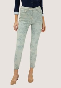 Jeans de impresión floral azul claro en un corte ajustado con una cintura alta, que cuentan con bolsillos y costuras de contraste, combinados con tacones beige.