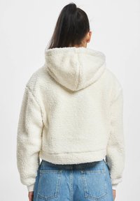 Kremfarget cropped hoodie laget av teksturert fleece, med hette og ribbestrikkede mansjetter, parret med høyt liv denimbukser.