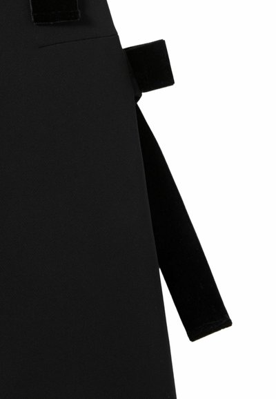 Grembiule di stoffa nera con una lunga cinghia che si estende da un lato e una chiusura in velcro vicino al bordo superiore, isolato su sfondo bianco.