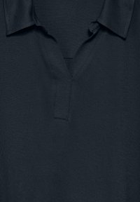 Tummansininen poolopaita, jossa on kauluksen band ja V-mallinen aukko, valmistettu sileästä kankaasta. Ominaisuuksiin kuuluvat siistit ompeleet ja vähäiset suunnitteluedut.