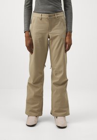 Pantalons de neige beiges avec un design à jambe droite, poches zippées et fermeture à bouton, fabriqués à partir d'un matériau durable et résistant à l'eau.