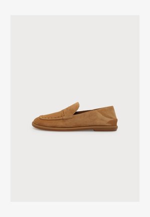 Mocassin en daim beige clair avec une semelle en caoutchouc basse, des coutures apparentes et un détail fente à penny classique, présenté en profil gauche sur fond blanc.