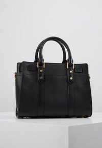 Černá kožená kabelka s texturovaným povrchem, dvojitými horními uchy, zlatými doplňky a dvěma předními kapsami. Čtvercový tvar s pevným designem.