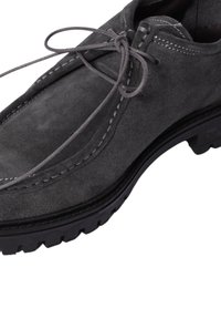 Scarpa in suede grigia con punta tonda, suola in gomma nera piatta e lacci grigi. La cucitura a contrasto lungo la parte superiore aggiunge un dettaglio sottile.