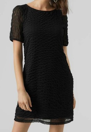 Robe noire avec des manches courtes texturées, présentant un motif ondulé sur l'ensemble. Le tissu semble léger et légèrement transparent au niveau de l'ourlet.
