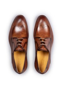 Bruine leren geklede schoenen met perforaties, ronde neus en vetersluiting. Heeft een gladde afwerking en een contrasterende binnenvoering.