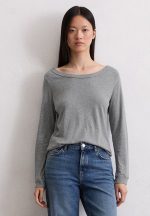Graues Langarmshirt mit weitem Bootsausschnitt, weichem Stoff und engen Bündchen, kombiniert mit hochgeschlossenen blauen Jeans.
