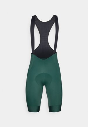 Grøn cykelbibs med sorte stropper, der har et polstret chamois-område og en glat tekstur. Designet inkluderer en mesh-ryg for ventilation.