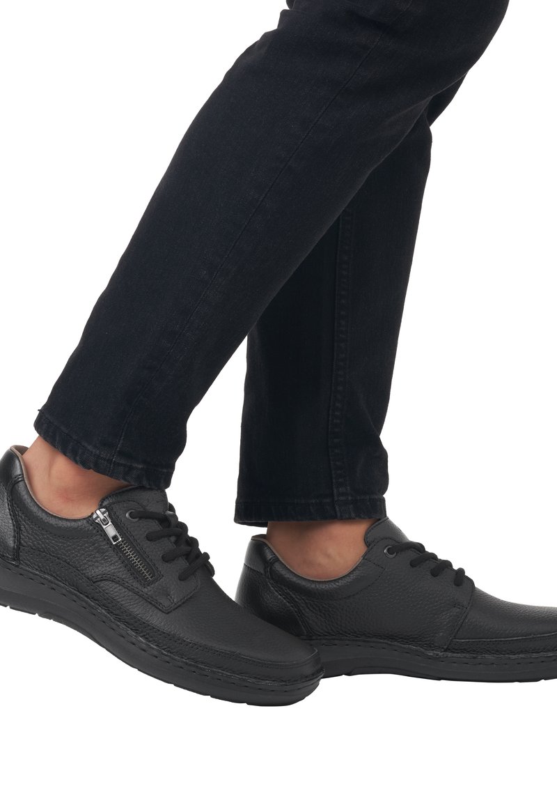 Black leather shoes with a textured finish, lace-up closure, and a side zipper. The sole is flat and slightly raised for comfort.