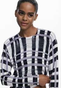 Valge, tumesinine ja lavendlivärvi pikakä sleevesweater, millel on ruuduline muster. Pehme, kvaliteetne kudumine, ümar kaelus ja soonikkoes varrukapead.