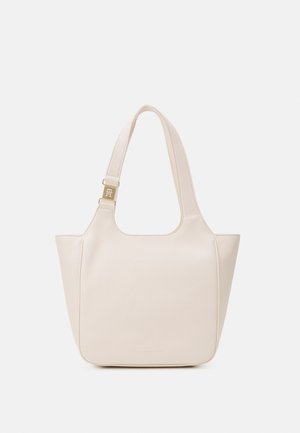 Bolso tote de cuero color crema con correas anchas y herrajes dorados, con un sutil grabado de la marca cerca del centro inferior.