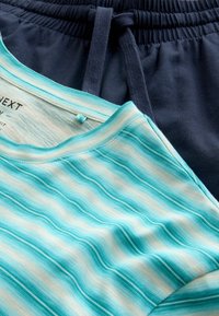 Chemise à manches courtes rayée turquoise et blanche superposée sur un short bleu marine à cordon de serrage avec taille élastique.