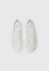Baskets blanches au texture lisse, avec un bout rond, un laçage et un branding minimaliste sur le côté. Semelles et oeillets de couleur crème.