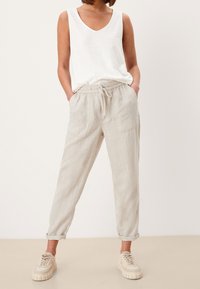 Lätta linbyxor i beige med dragsko i midjan och två framfickor. Matchas med en vit ärmlös topp och beiga sneakers.