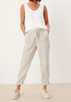 Leichte Leinenhosen in Beige mit einem Kordelzugbund und zwei vorderen Taschen. Kombiniert mit einem weißen ärmellosen Oberteil und beigen Sneakers.
