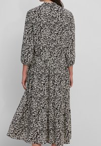 Zwart-witte jurk met patroon, driekwart mouwen, een gelaagde rok en een samengestikte taille. Zachte stof met een vloeiende silhouet.