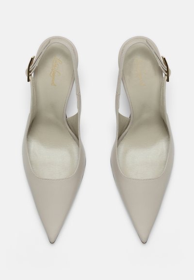 Paar beige spitze Slingback-Schuhe aus Leder mit goldenen Schnallriemen, von oben auf weißem Hintergrund betrachtet.