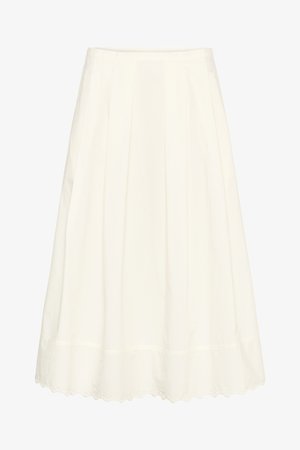 Fehér midi szoknya redőkkel és hullámos szegéllyel, melyen kivágásos hímzési részlet található.