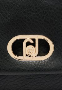 Schwarze, texturierte Lederhandtasche mit einem goldfarbenen Metallverschluss, der ineinander geschlungene Buchstaben zeigt und das schlanke, moderne Design betont.
