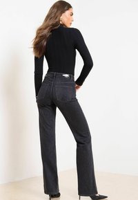 Črne široke kavbojke s teksturiranim vzorcem, ki imajo visok pas in zadnji žep. Material izgleda kot denim, z rahlim sijajem.