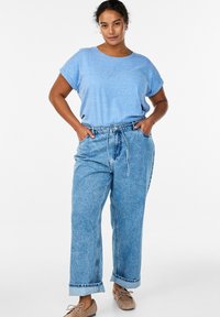 Hellblaues T-Shirt mit kurzen Ärmeln, lockerer Schnitt. Hoch taillierte, lockere blaue Jeans mit Bindegürtel und Vordertaschen. Weiche Textur.