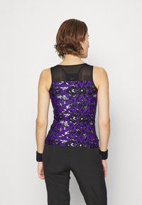 Lila und schwarze Tanktop mit Paillettenverzierungen im Tiermuster. Ein Netzpaneel auf der Rückseite sorgt für eine besondere Textur.