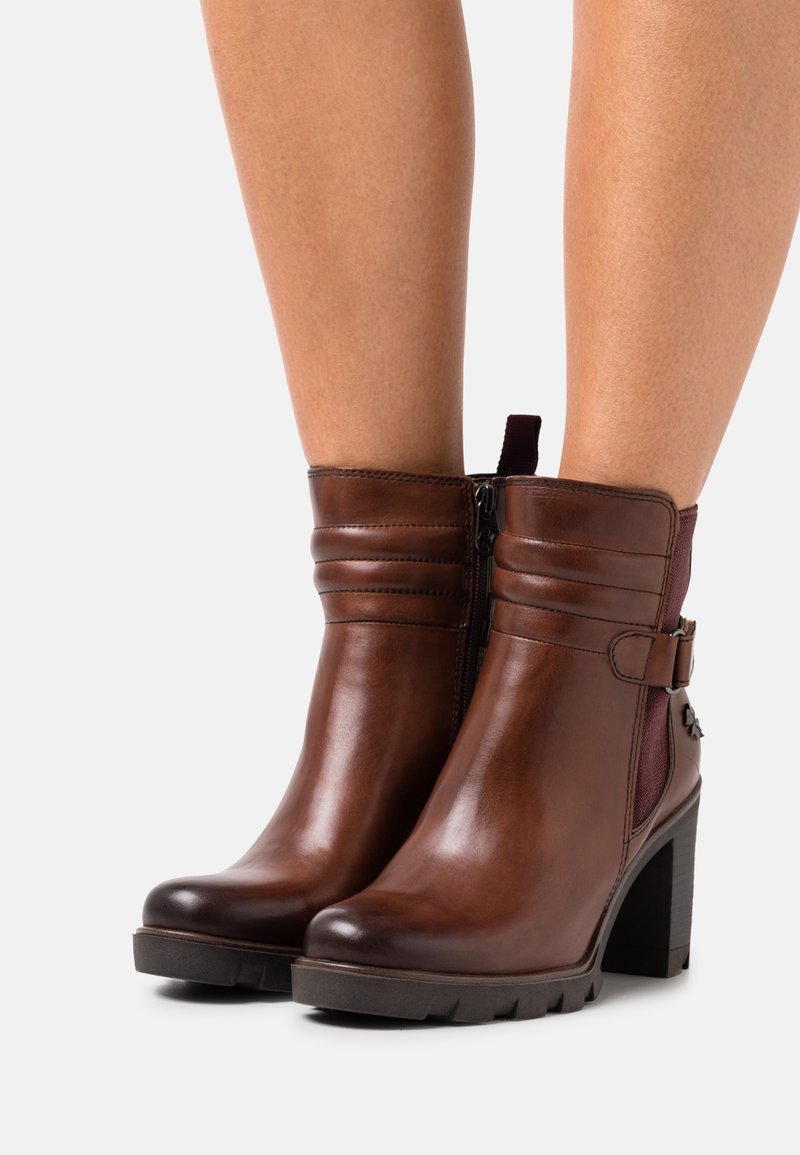 Bottes chelsea en cuir marron avec un talon carré, dotées d'une fermeture éclair latérale, de coutures horizontales et d'un panneau d'accent maroon.