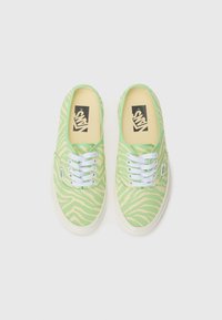 Green canvas sneakers featuring a zebra stripe pattern, white laces, and rubber soles. Inside has yellow lining and a black logo.
