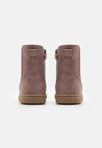 Stivali alla caviglia in suede marrone con una texture morbida, suola in gomma a contrasto e due piccole asole sui lati per una calzata più facile.