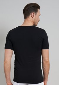 T-shirt noir à manches courtes au design ajusté, fabriqué en tissu en coton lisse, avec un col large et une couleur unie sans motifs.