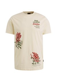 T-shirt en coton couleur crème avec des graphismes de piments rouges et un texte vert. Présente des manches courtes et un col rond.
