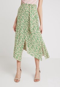 Blommig midikjol med ett grönt och rosa mönster, med asymmetrisk fåll och bältesdetalj. Tillverkad i lätt tyg.