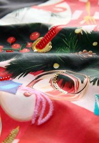 Textile featuring vibrant holiday-themed illustrations. Rich colors include red, green, and gold with textured embroidery and sequins.