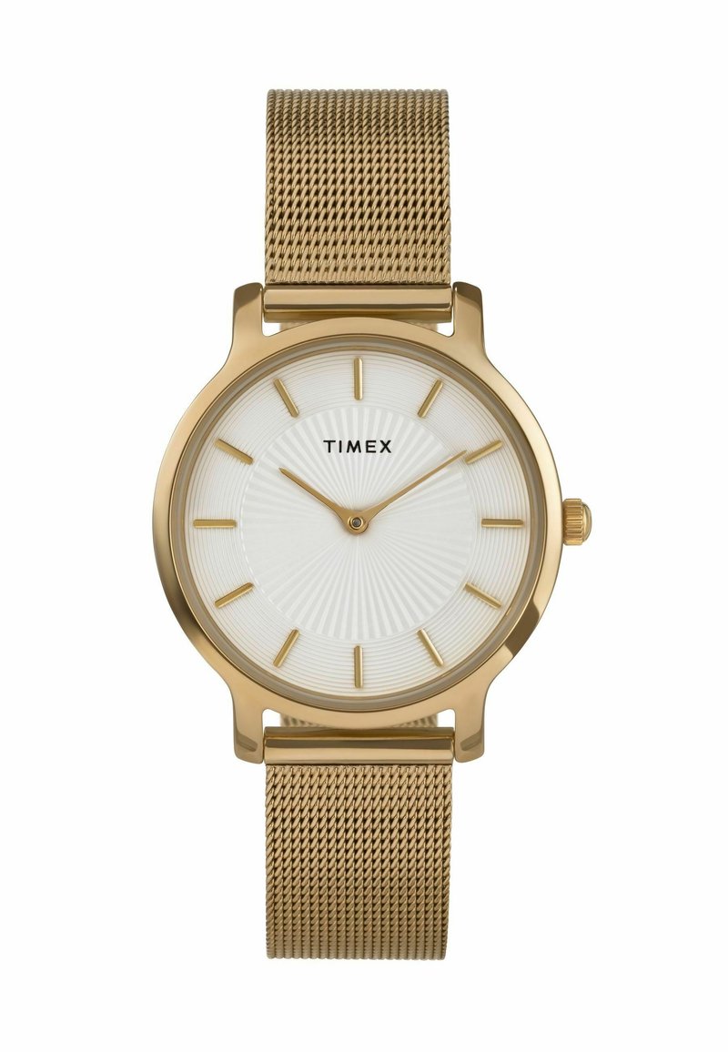 Kuldtono Timex kell valge tekstureeritud kelladiialiga, kuldsete tunni markeritega ja võrksangaga. Omab ümmargust korpust ja minimalistlikku disaini.