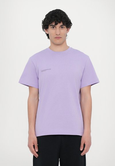 Levandų spalvos crew neck marškinėliai iš medvilnės, trumpomis rankovėmis, su maža tekstine detale kairėje pusėje. Lygi tekstūra, laisvas siluetas.