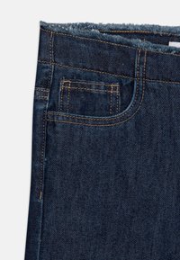 Falda de mezclilla en azul oscuro con dobladillo deshilachado, que presenta un bolsillo frontal y costuras en contraste. Textura suave y diseño clásico.