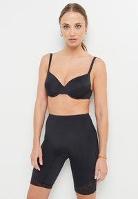 Soutien-gorge noir sans couture avec bonnets moulés, bretelles réglables et shorts de vélo taille haute ornés de dentelle à l'ourlet. Texture lisse.