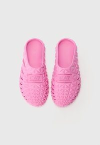 Sapatos de plástico rosa, tipo chinelo, com um padrão texturizado em diamante e um logotipo em destaque na lateral. Superfície interior lisa.