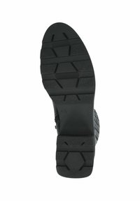 Suela de zapato de goma negra con un patrón de agarre texturizado, que incluye acentos hexagonales y lineales. Tamaño marcado como 4½.