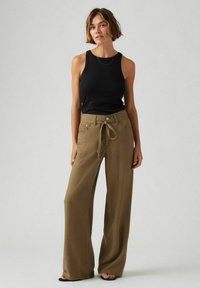 Svart tanktopp med ribbet tekstur, paret med vide kaki bukser som har snøring i midjen og frontlommer.