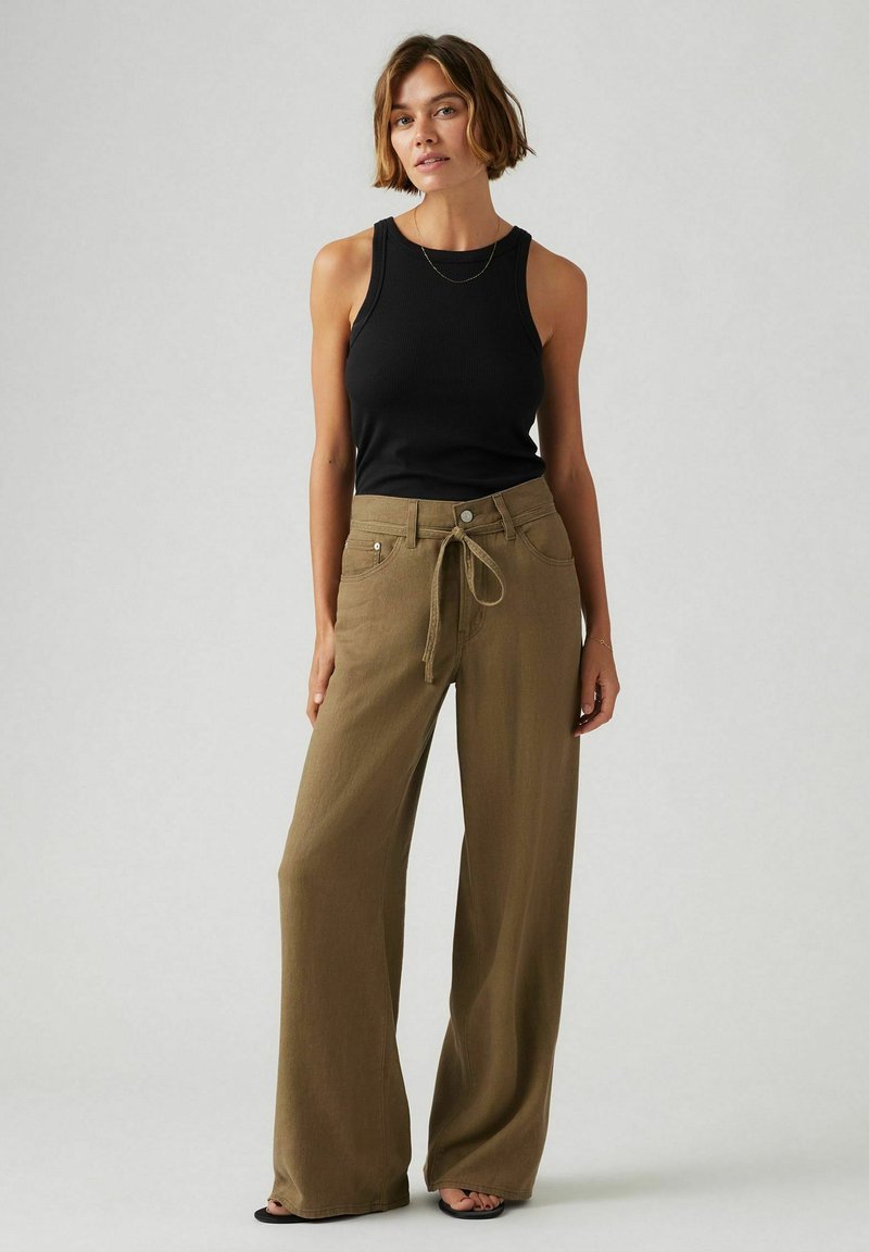 Débardeur noir à texture côtelée, associé à un pantalon large en khaki avec taille à cordon et poches avant.